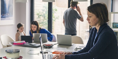 A mother and father work from home as their children play in the kitchen. 