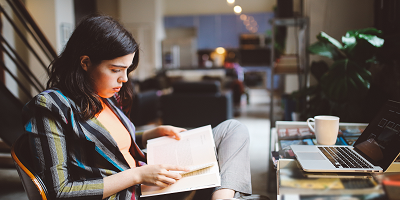 Young female professional reading a book at desk