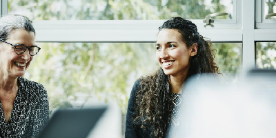 Professional woman sitting in a meeting at her workplace with her mentor by her side. 