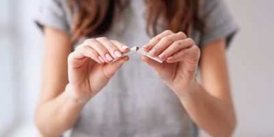 Woman breaking a single cigarette in her hands. 