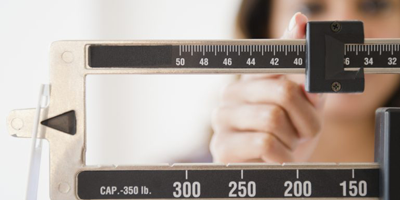 A female weighing herself on a scale. 