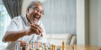 Laughing senior man playing chess