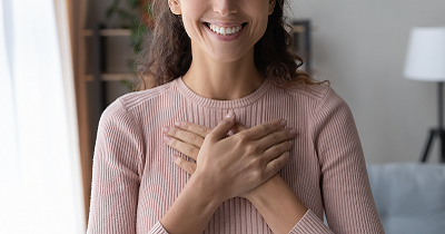 Woman with hands crossed over heart practicing gratitude