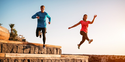 A male and female running in an outdoor trail indicating they live a healthy lifestyle.