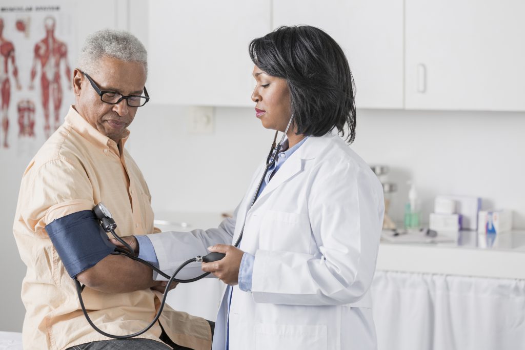 African American doctor taking a patient’s blood pressure.