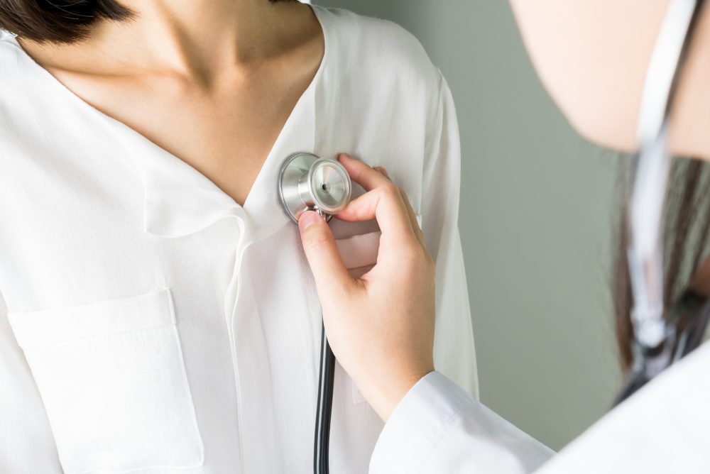 Close-up of a doctor holding a stethoscope on someone’s chest.
