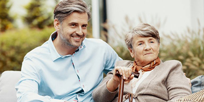 A son sits with his elderly mother.