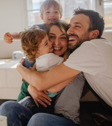 Young family with two sons embracing as they make special memories at home. 