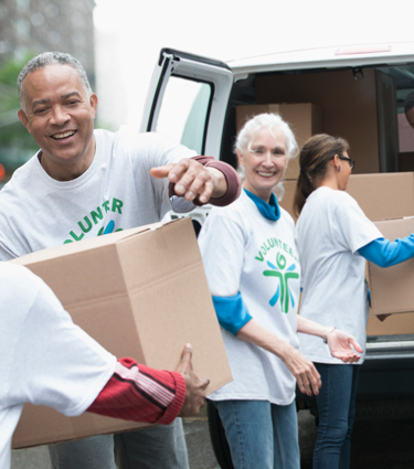 A group of volunteers working together to load a van with supplies.