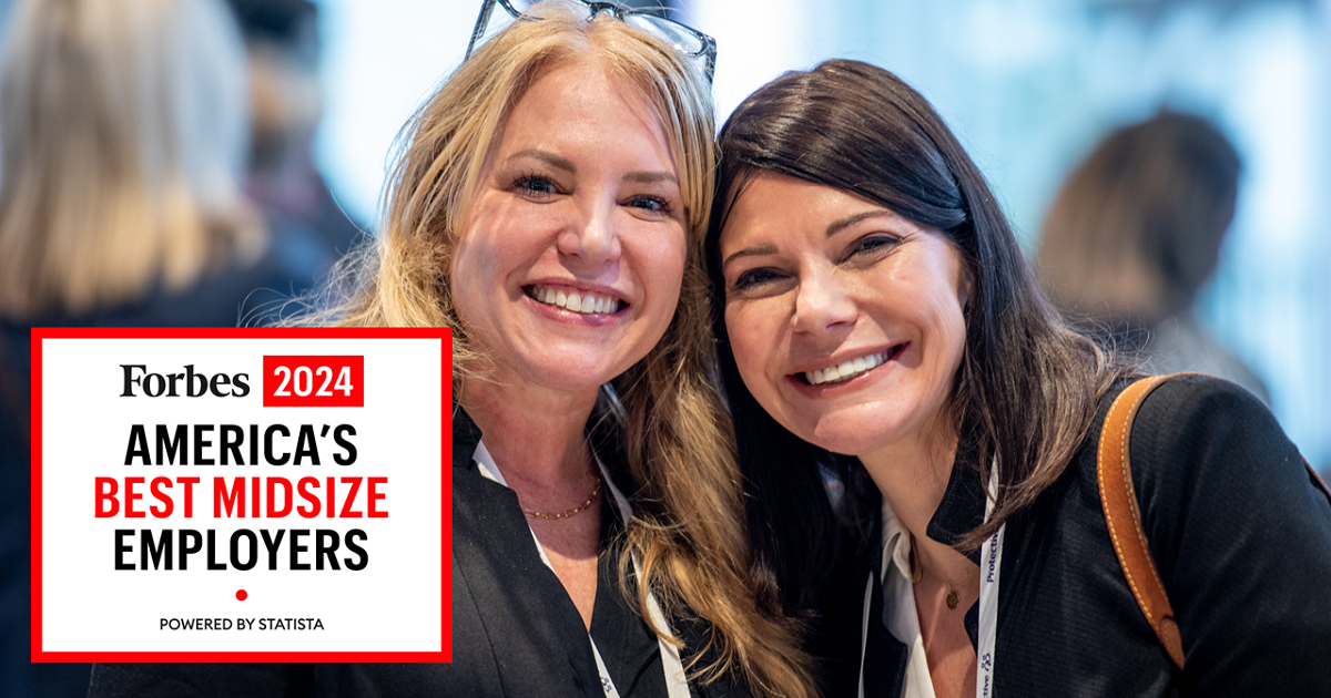Two women smiling at camera at a business event