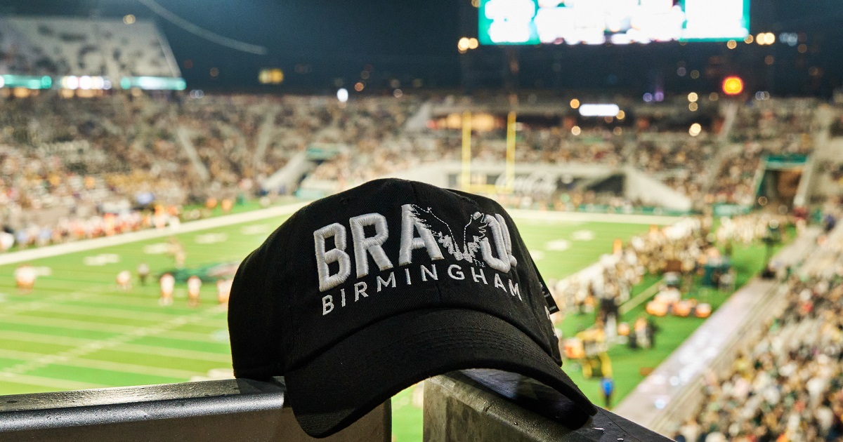 Fly V Bravo hat on rail at Protective Stadium with field in background
