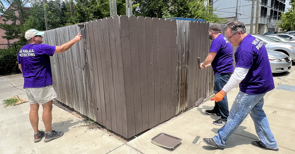 Protective Birmingham teammates painting fence at Ronald McDonald House