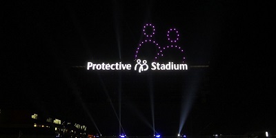Protective Stadium sign lit with drone show in sky